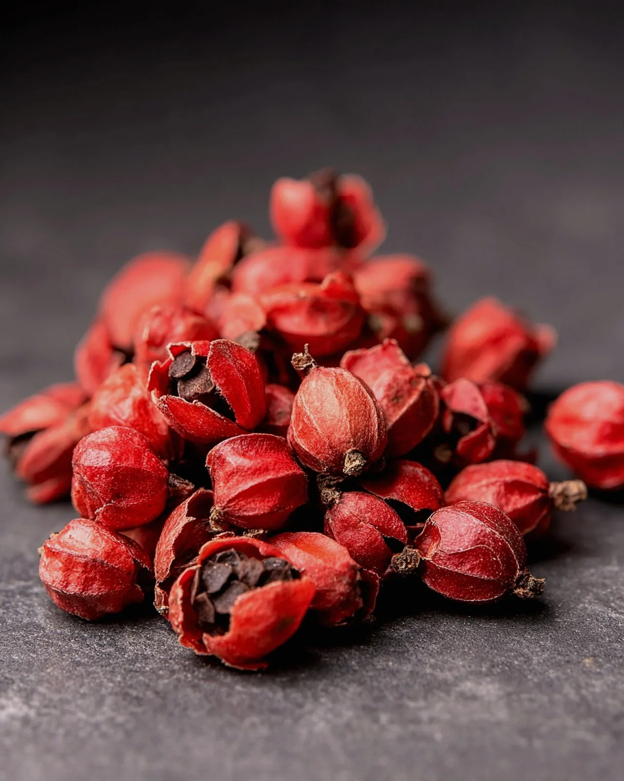 A heap of pink peppercorns on dark slate